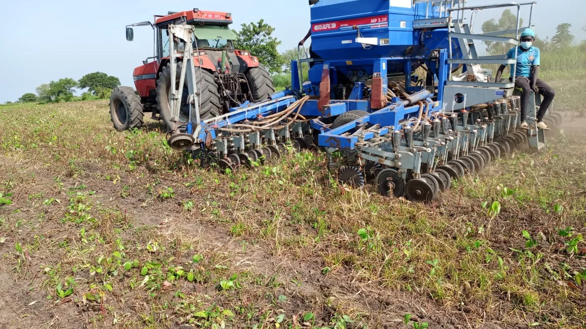 A tractor pulling a seed planter through a field at Normah's Amuru farm.